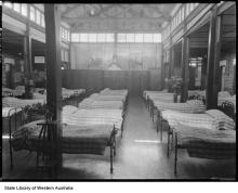 A black and white photograph of the dormitory at Castledare. A large number of metal framed beds occupy the room, and lying on top of each bed is an identical striped quilt. A statue of Mary and Jesus overlooks the beds.