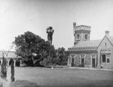 A black and white photograph of the stone-masonry front of St Francis House. There are several trees and a large lawn.