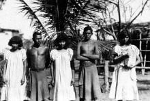 A black and white photograph of a small group of people at Groote Eyelandt Mission. They are assembled in a row, preparing for their photograph to be taken. 