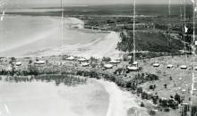 A black and white photograph of Kahlin Compound taken from an aeroplane. There are several buildings in the compound, and the shores of Cullen Bay and Mindil Beach are visible.