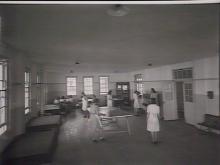 A black and white photograph of a room inside a building of Parramatta Girls' Industrial School. Inside the room are several girls, some of whom are playing table tennis, while others are at a piano.