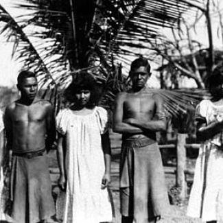 A black and white photograph of a small group of people at Groote Eyelandt Mission. They are assembled in a row, preparing for their photograph to be taken. 