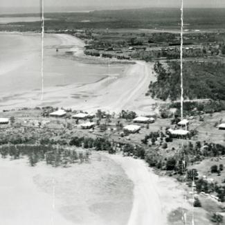 A black and white photograph of Kahlin Compound taken from an aeroplane. There are several buildings in the compound, and the shores of Cullen Bay and Mindil Beach are visible.