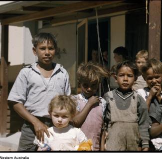 A colour photograph of several  young children at Marribank Mission. They are outside in the open, standing together in a small group. 